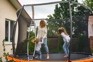 Anne ve çocuk kızları bir trambolin üzerinde atlama