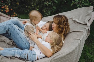 bir hamakta eğleniyor çocuk anne. Anne ve çocuklar bir hamak. Aile ile çocuk bahçesinde vakit geçiriyor.
