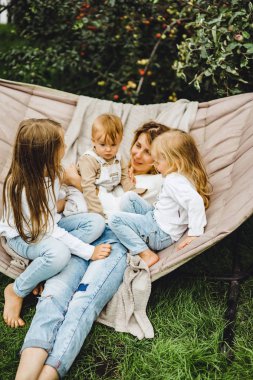 bir hamakta eğleniyor çocuk anne. Anne ve çocuklar bir hamak. Aile ile çocuk bahçesinde vakit geçiriyor.
