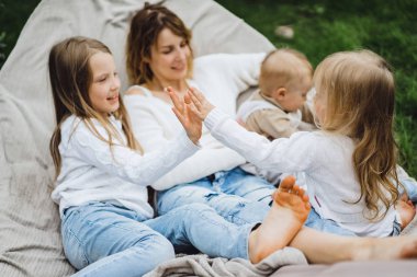 bir hamakta eğleniyor çocuk anne. Anne ve çocuklar bir hamak. Aile ile çocuk bahçesinde vakit geçiriyor.