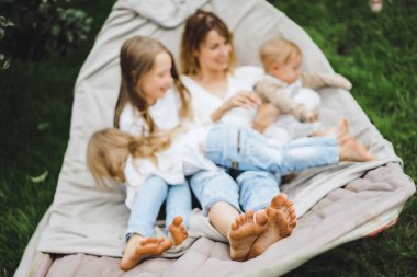 bir hamakta eğleniyor çocuk anne. Anne ve çocuklar bir hamak. Aile ile çocuk bahçesinde vakit geçiriyor.