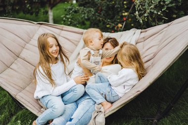 bir hamakta eğleniyor çocuk anne. Anne ve çocuklar bir hamak. Aile ile çocuk bahçesinde vakit geçiriyor.