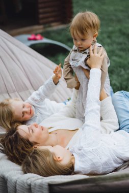 bir hamakta eğleniyor çocuk anne. Anne ve çocuklar bir hamak. Aile ile çocuk bahçesinde vakit geçiriyor.