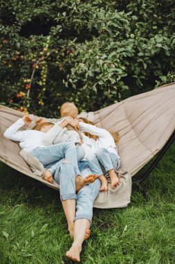 bir hamakta eğleniyor çocuk anne. Anne ve çocuklar bir hamak. Aile ile çocuk bahçesinde vakit geçiriyor.