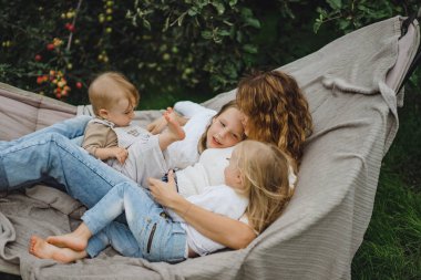 bir hamakta eğleniyor çocuk anne. Anne ve çocuklar bir hamak. Aile ile çocuk bahçesinde vakit geçiriyor.