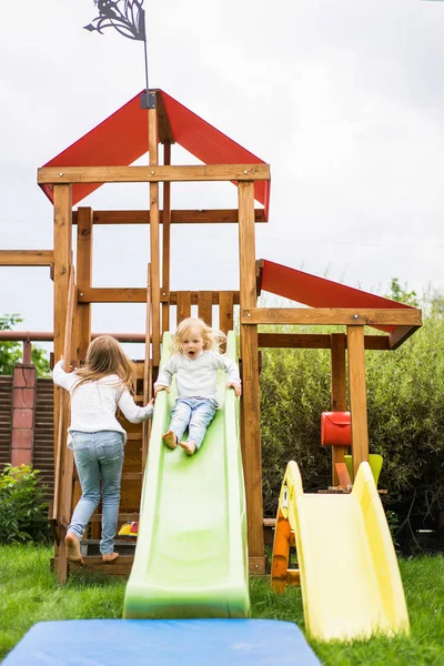 children ride from the children\'s slide, sisters play together in the garden, children play and have fun in the yard