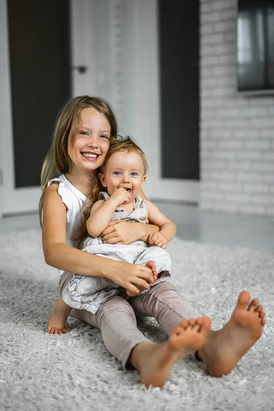 sister is messing with her younger brother. Sister is holding a little brother. Siblings.