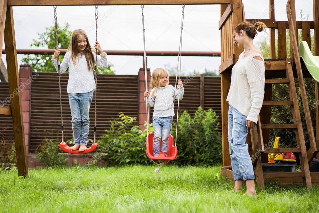 children on the swing. girls sisters swinging on a swing in the yard. summer fun.