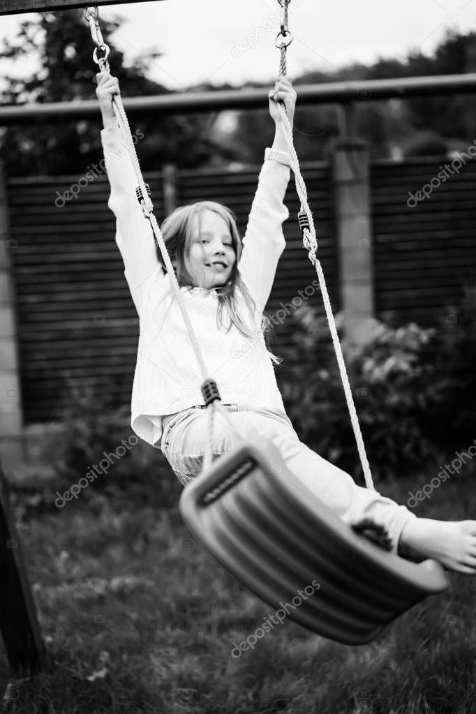 child on the swing. girl swinging on a swing in the yard. summer fun.