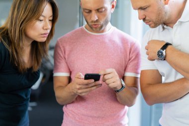 close up.boss iş arkadaşlarına akıllı telefon ekranında bilgi gösterir. gençler haberleri paylaşır, akıllı telefonda video gösterir,