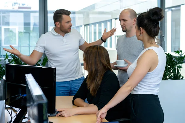 Full concentration at work. Group of young business people working and communicating while sitting at the office desk together with colleagues sitting in the background