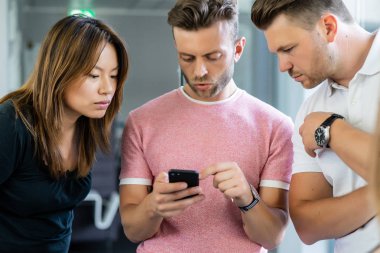 close up.boss iş arkadaşlarına akıllı telefon ekranında bilgi gösterir. gençler haberleri paylaşır, akıllı telefonda video gösterir,