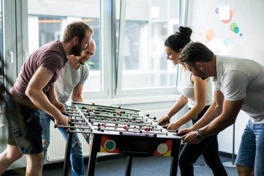 ofiste masa futbolu oynayan ve birlikte eğlenmek mutlu yöneticileri