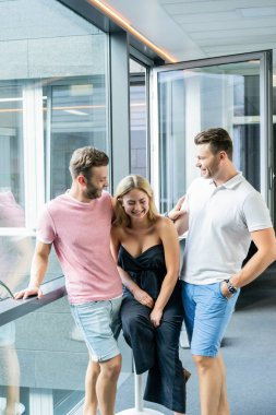 Geniş pencereli bir ofiste duran bir grup genç.