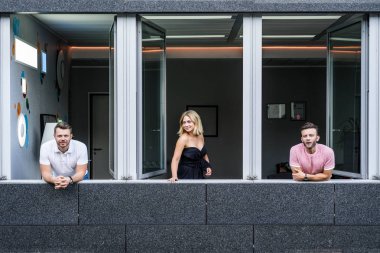 Geniş pencereli bir ofiste duran bir grup genç.