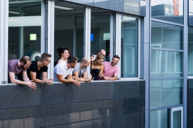 Geniş pencereli bir ofiste duran bir grup genç.