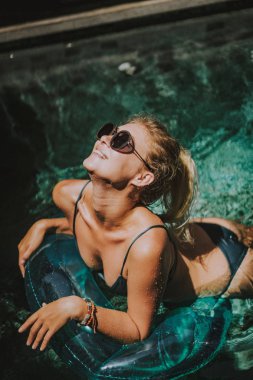 erkek tatilde. Güzel genç kadın havuzda şişme bir çember üzerinde yüzüyor.