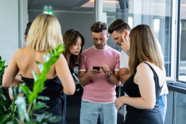 close up.boss iş arkadaşlarına akıllı telefon ekranında bilgi gösterir. gençler haberleri paylaşır, akıllı telefonda video gösterir,