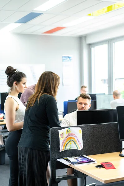 Full concentration at work. Group of young business people working and communicating while sitting at the office desk together with colleagues sitting in the background