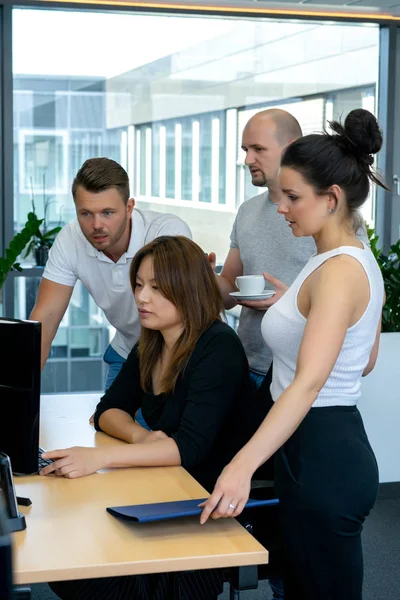 Full concentration at work. Group of young business people working and communicating while sitting at the office desk together with colleagues sitting in the background