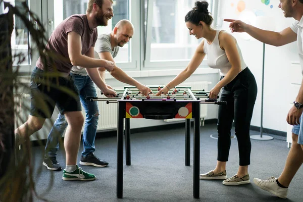 happy managers playing table football at office and having fun together