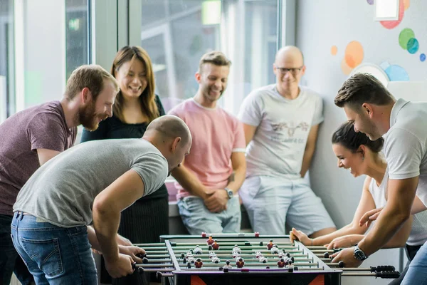 happy managers playing table football at office and having fun together