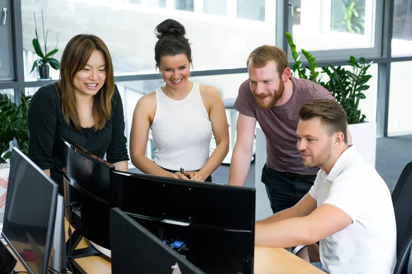 Full concentration at work. Group of young business people working and communicating while sitting at the office desk together with colleagues sitting in the background