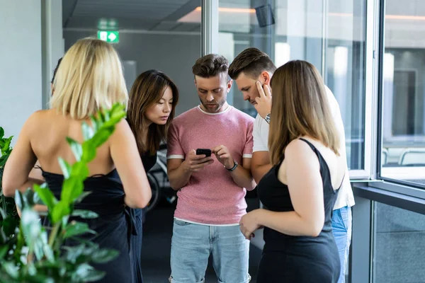 close up.boss shows colleagues information on the smartphone screen.  young people share news, show videos on a smartphone, discuss