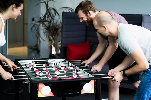 happy managers playing table football at office and having fun together