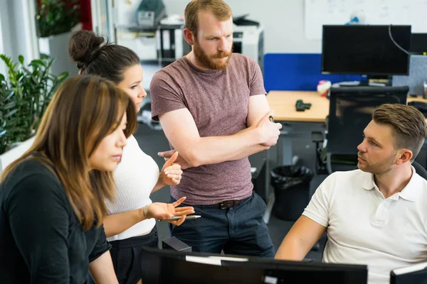 Full concentration at work. Group of young business people working and communicating while sitting at the office desk together with colleagues sitting in the background