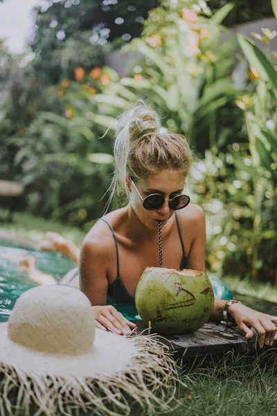 beautiful young woman swims in the pool and drinks coconut. female on vacation