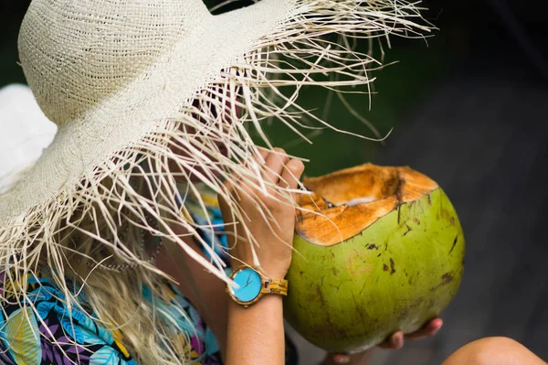 Hermosa mujer joven en un sombrero de paja está acostado en una tumbona y d — Foto de Stock