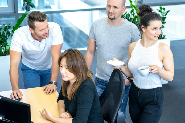 Full concentration at work. Group of young business people working and communicating while sitting at the office desk together with colleagues sitting in the background