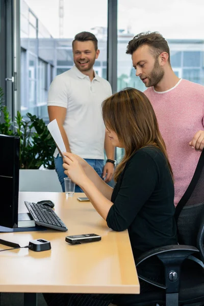 Full concentration at work. Group of young business people working and communicating while sitting at the office desk together with colleagues sitting in the background