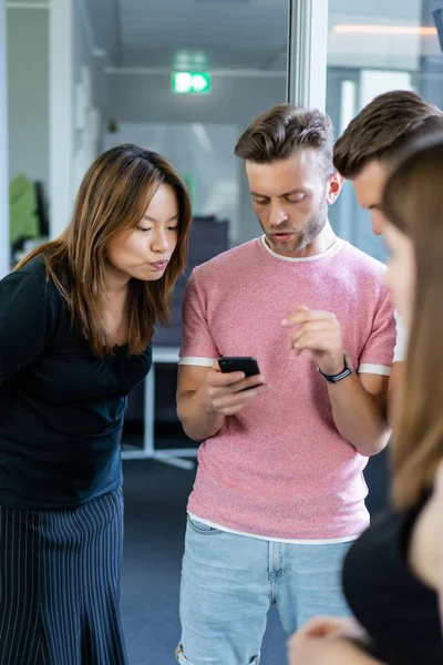 close up.boss shows colleagues information on the smartphone screen.  young people share news, show videos on a smartphone, discuss