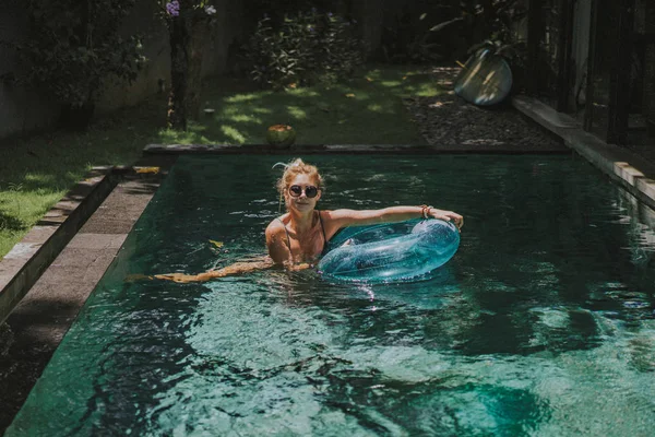 女性在度假 美丽的年轻女子在一个充气圈的池子里游泳 — 图库照片