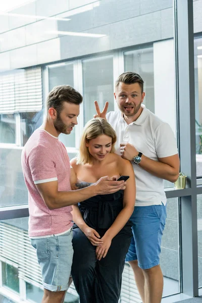 close up.boss shows colleagues information on the smartphone screen.  young people share news, show videos on a smartphone, discuss