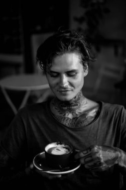 Yakışıklı dövmeli adam bir kafede kahvaltı yapıyor, kahve içiyor. dövmeler adam