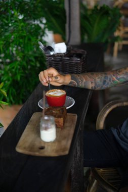 Yakışıklı dövmeli adam bir kafede kahvaltı yapıyor, kahve içiyor. dövmeler adam