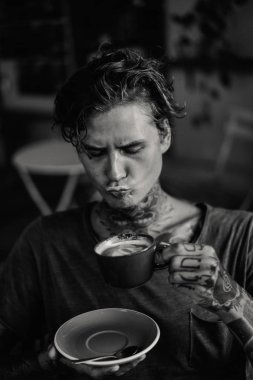Yakışıklı dövmeli adam bir kafede kahvaltı yapıyor, kahve içiyor. dövmeler adam