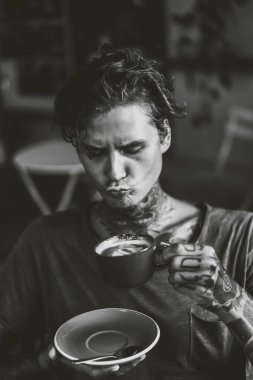 Yakışıklı dövmeli adam bir kafede kahvaltı yapıyor, kahve içiyor. dövmeler adam