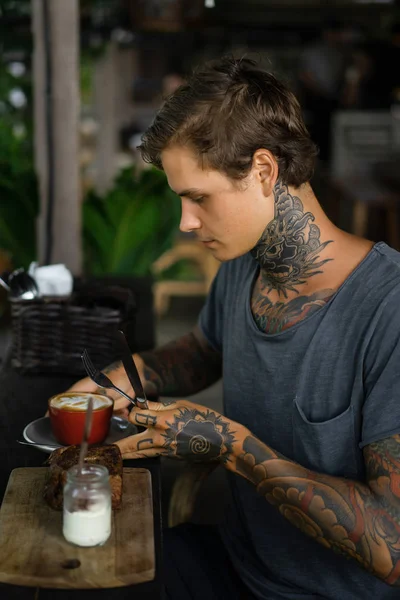 カフェで朝食を食べ コーヒーを飲むハンサムな入れ墨の男 入れ墨の男 — ストック写真