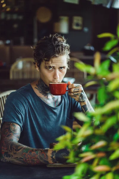 handsome tattooed man having breakfast in a cafe, drinking coffee. man in tattoos