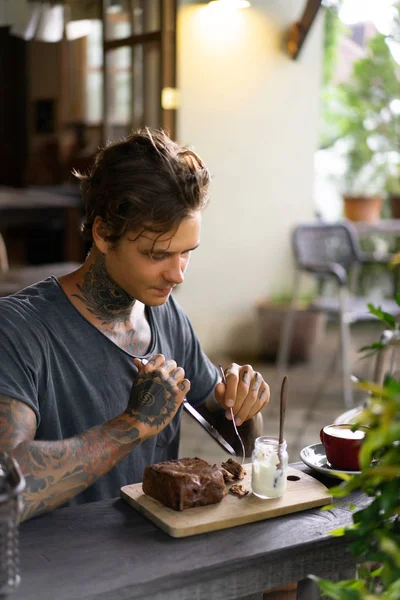 handsome tattooed man having breakfast in a cafe, drinking coffee. man in tattoos