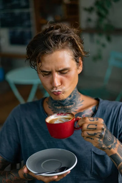 handsome tattooed man having breakfast in a cafe, drinking coffee. man in tattoos