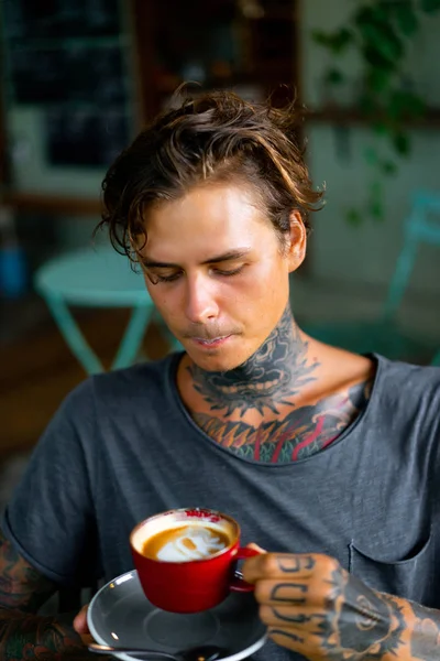 handsome tattooed man having breakfast in a cafe, drinking coffee. man in tattoos