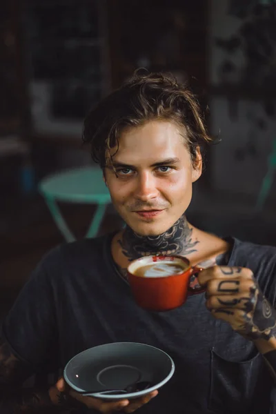 handsome tattooed man having breakfast in a cafe, drinking coffee. man in tattoos