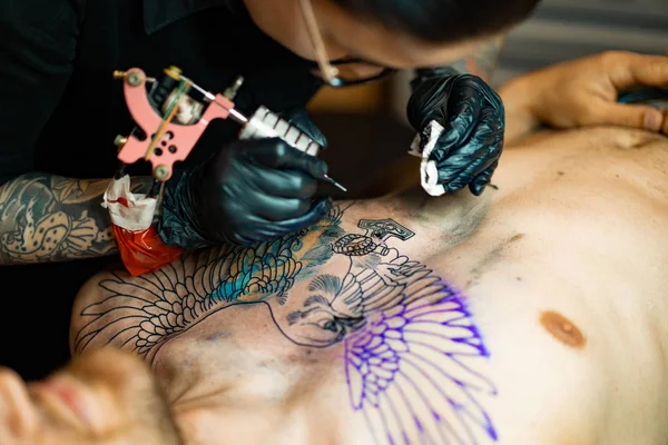 Tattoo salon process. A tattoo girl stuffed a tattoo. the process of stuffing a tattoo on the body. Hands close-up.