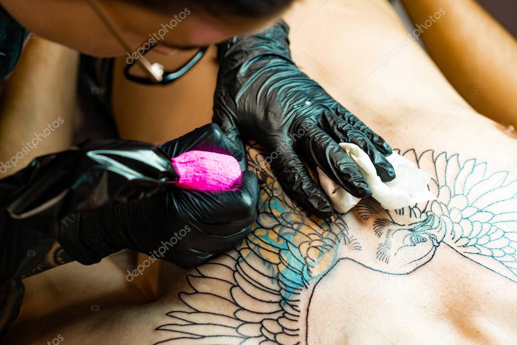 Tattoo salon process. A tattoo girl stuffed a tattoo. the process of stuffing a tattoo on the body. Hands close-up.