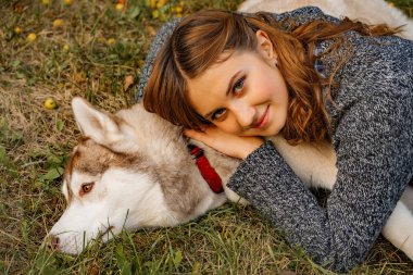 sonbahar parkında genç kadın bir husky köpek ile yürüyor.